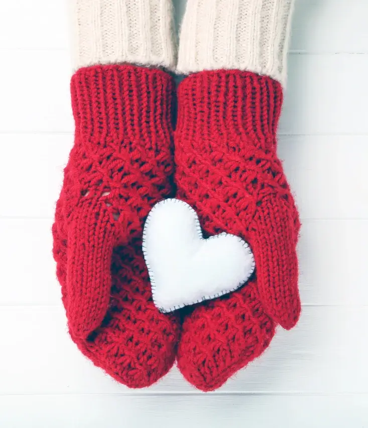 Two hands in red gloves holding a white felt heart